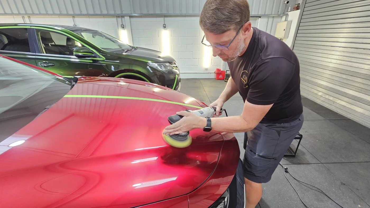 Machine polishing the bonnet of a red car